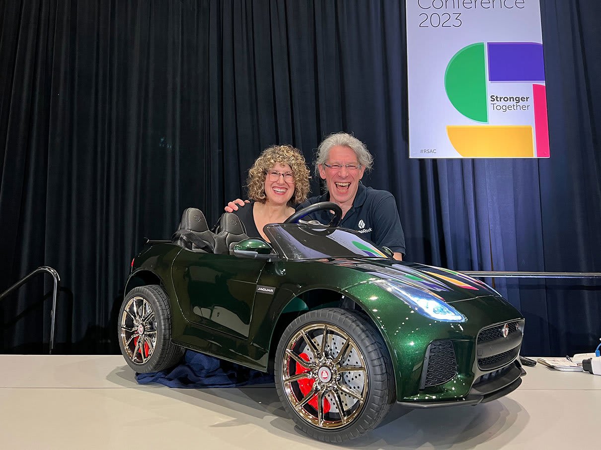 Eve Maler and Tim Vogt presented "Driving Smart Innovation – Connected Car Identity at Scale" at RSAC 2023. They are posing behind a green model car used for the demonstration.