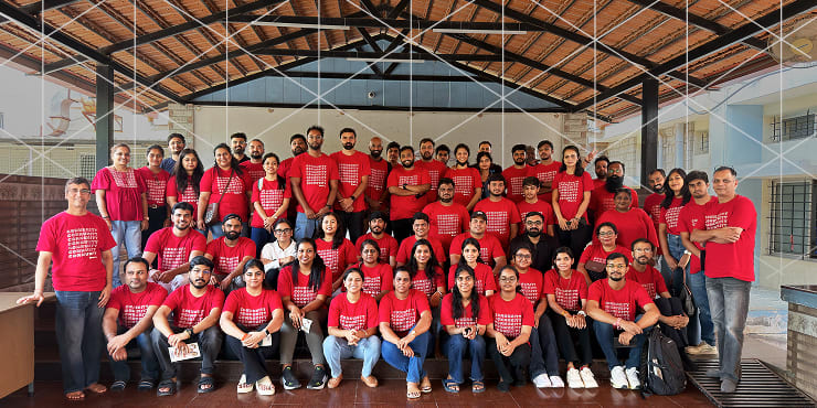 Large group photo of Ping Identity employees wearing matching red company shirts posing together under a pavilion
