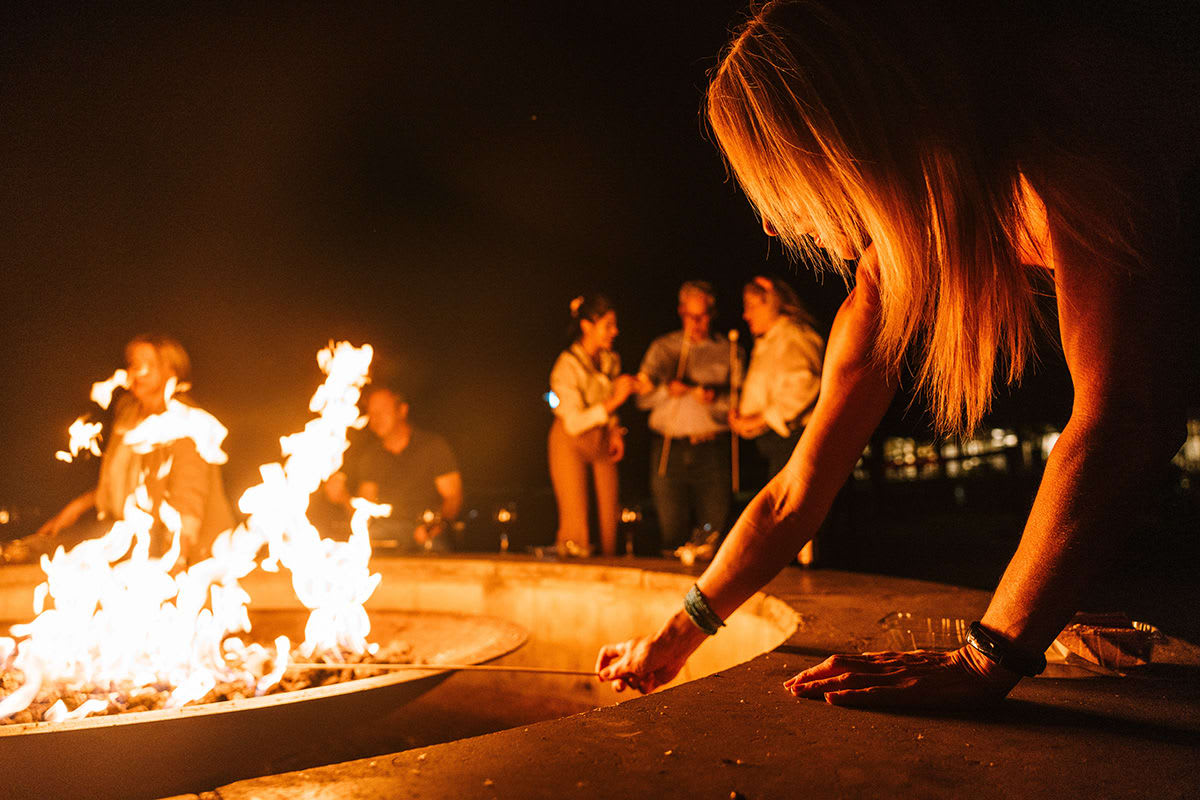 A photo of people gathered around a fire pit at nighttime.