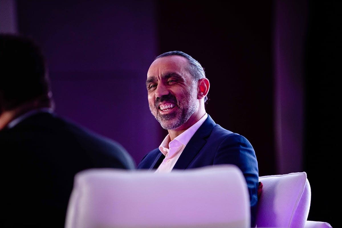 A photo of Adam Goodes, iDiC CEO & GO Foundation Co-Founder, smiling from the stage while taking part in a fireside chat.