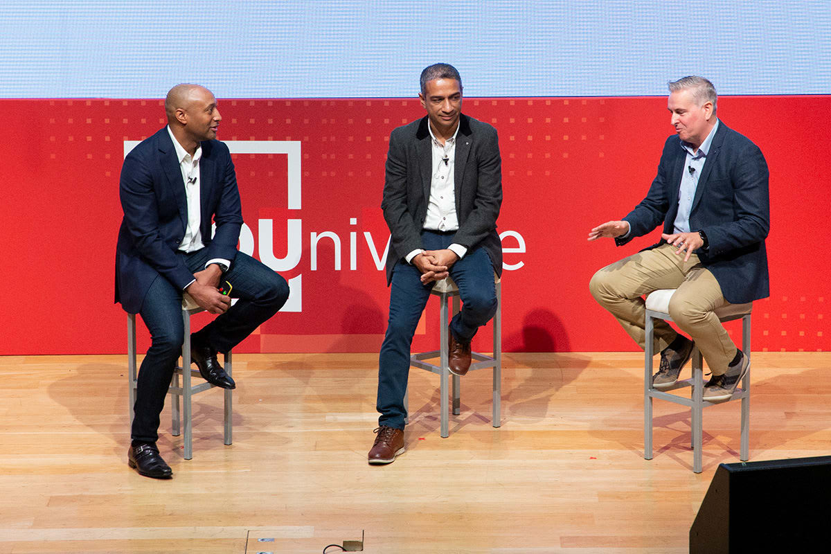 A photo of Aubrey Turner, Ping Identity Executive Advisor, and Three Ireland’s Hugh Crean and Amit Lall sitting on stools having a discussion on stage.