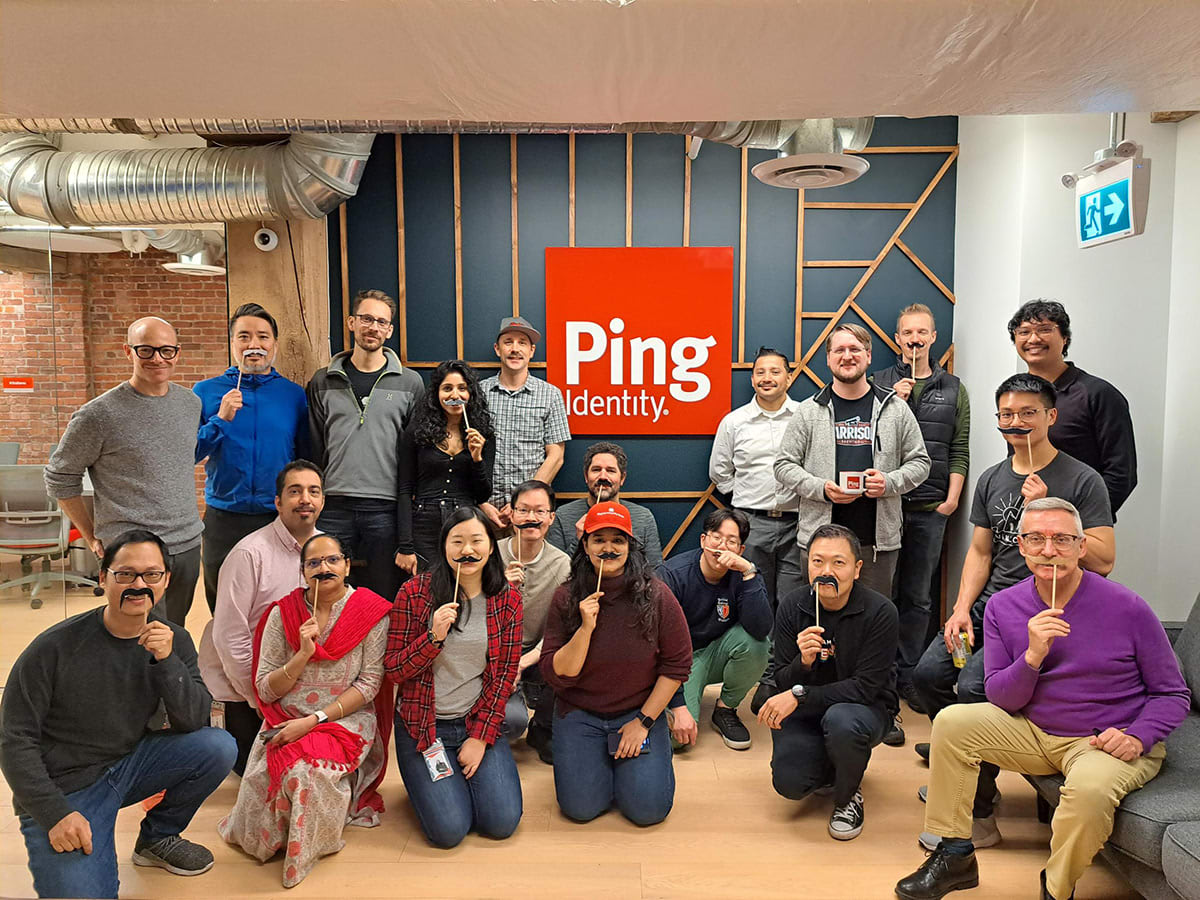A photo of a group of Ping Identity employees posing in the Vancouver office with many wearing fake mustaches.