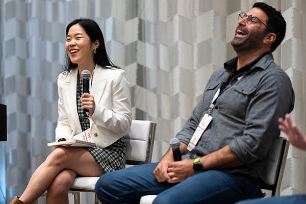 two speakers laughing on stage during closing session