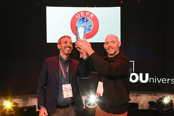 two award recipients holding up award onstage