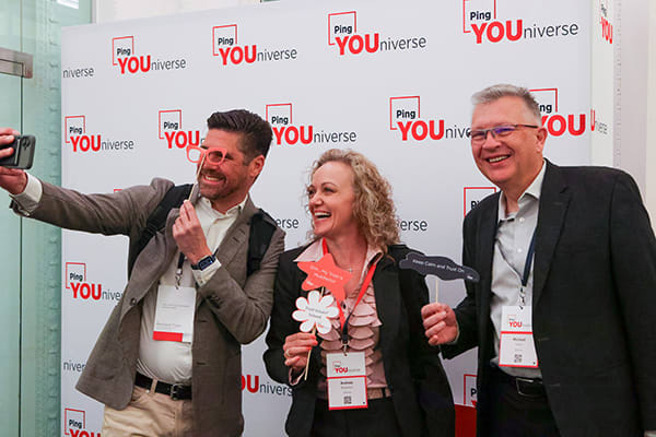 three attendees laughing and posing for selfie with props