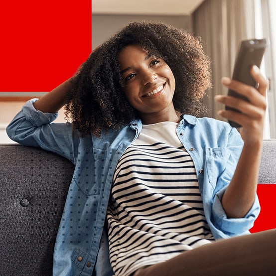 Young woman sitting on couch smiling while watching tv