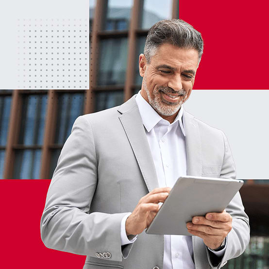 Man in a suit looking down at his tablet smiling