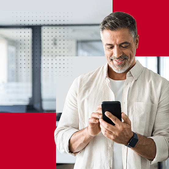 Man standing in office smiling while looking at phone