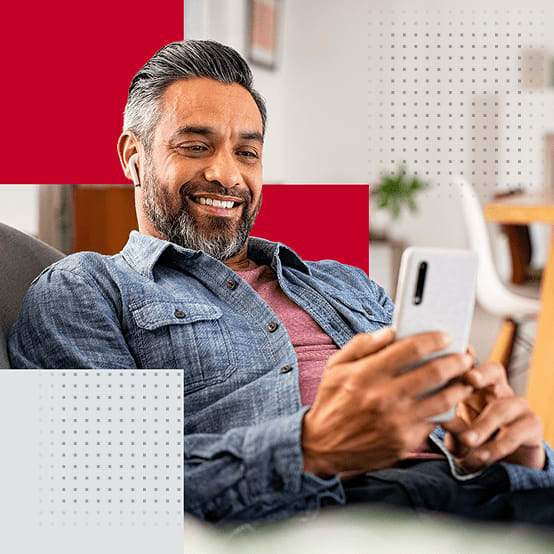 Man sitting on couch smiling while looking at phone