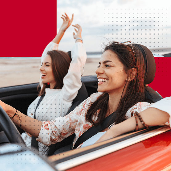 Two female friends riding in a car laughing