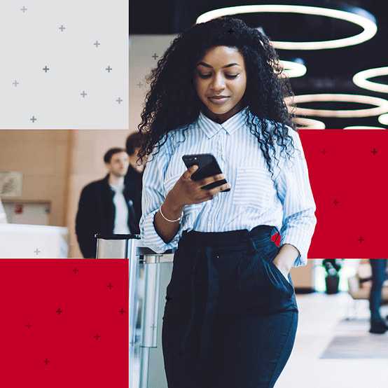 Woman looking down at phone while walking inside a lobby