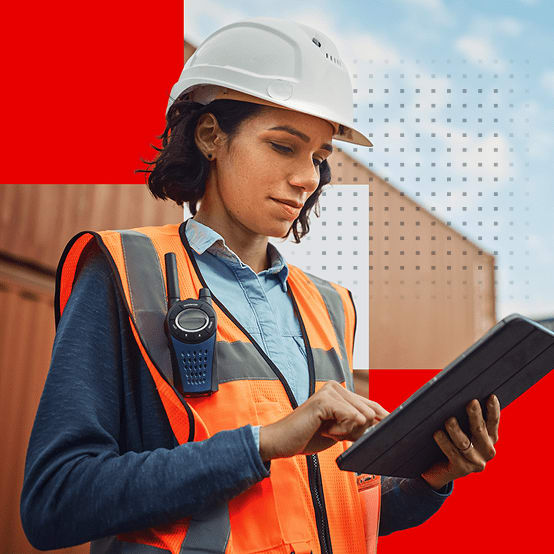 Female worker in a hard hat and safety vest using a tablet