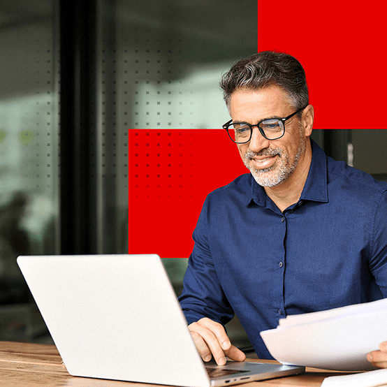 Man in office smiling while working on laptop