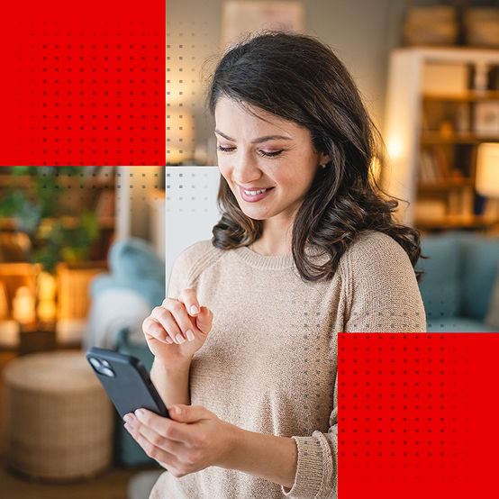 A smiling woman in a living room using her smartphone