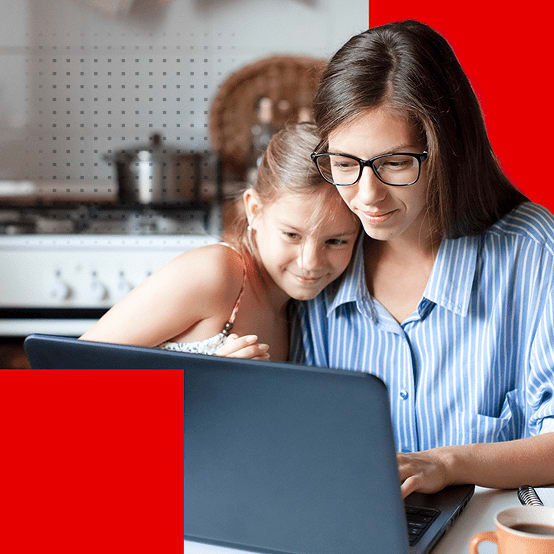 Adult and child smiling together using a laptop at a table