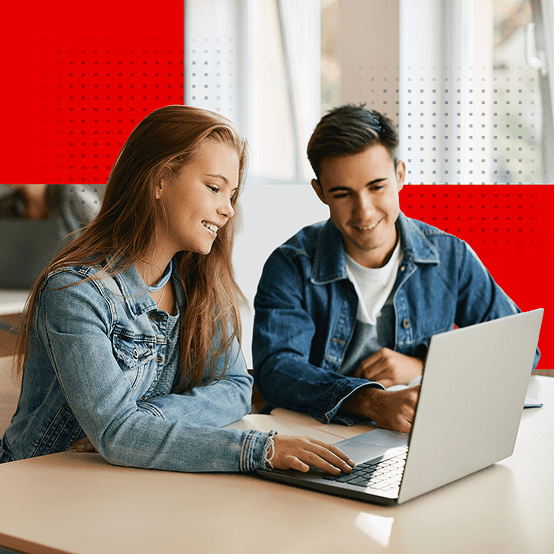 Two students collaborating on a laptop in a classroom