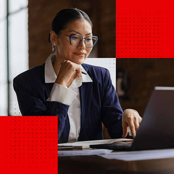 Woman sitting at desk smiling while working on laptop
