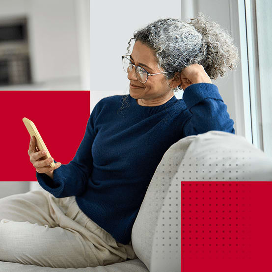 Woman sitting on couch smiling while looking at phone