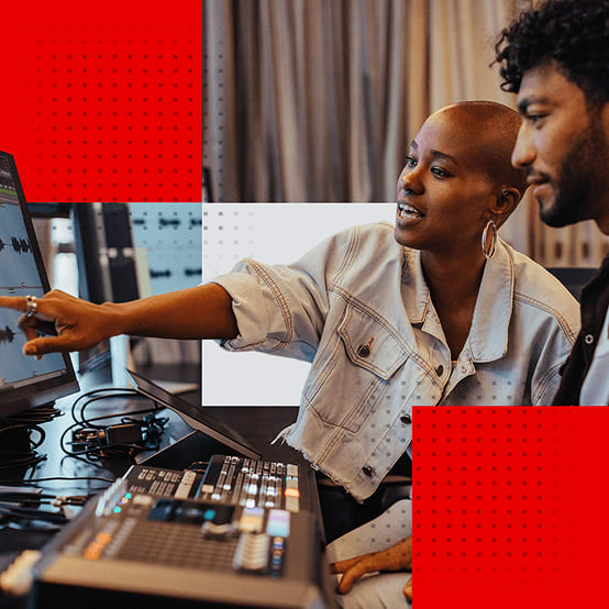 Two people editing audio at a computer in a studio