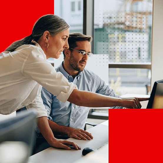 Two coworkers at a desk looking at a computer screen