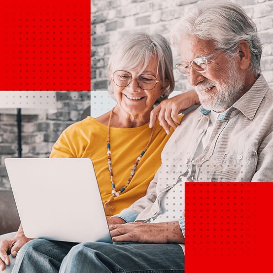 Elderly couple smiling while looking at a laptop
