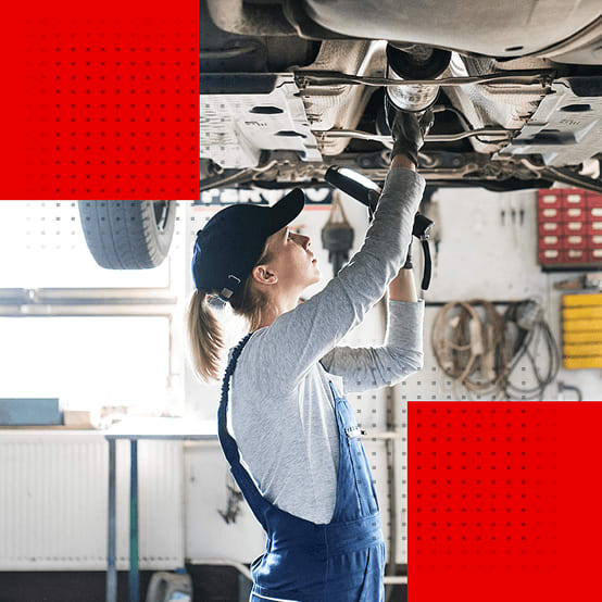 A mechanic inspecting the underside of a car on a lift