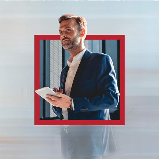 A man standing in a suit tapping on a tablet