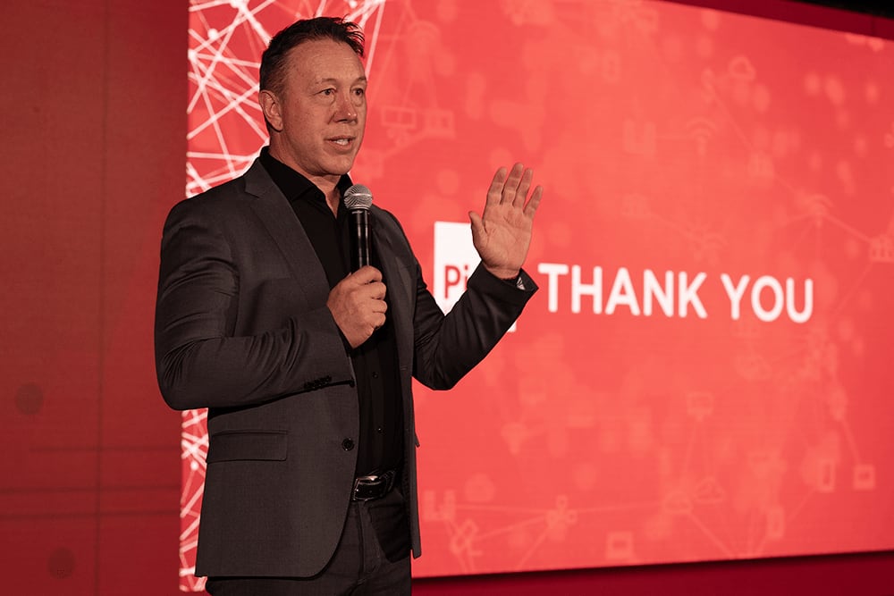 Man speaking at event with THANK YOU on screen
